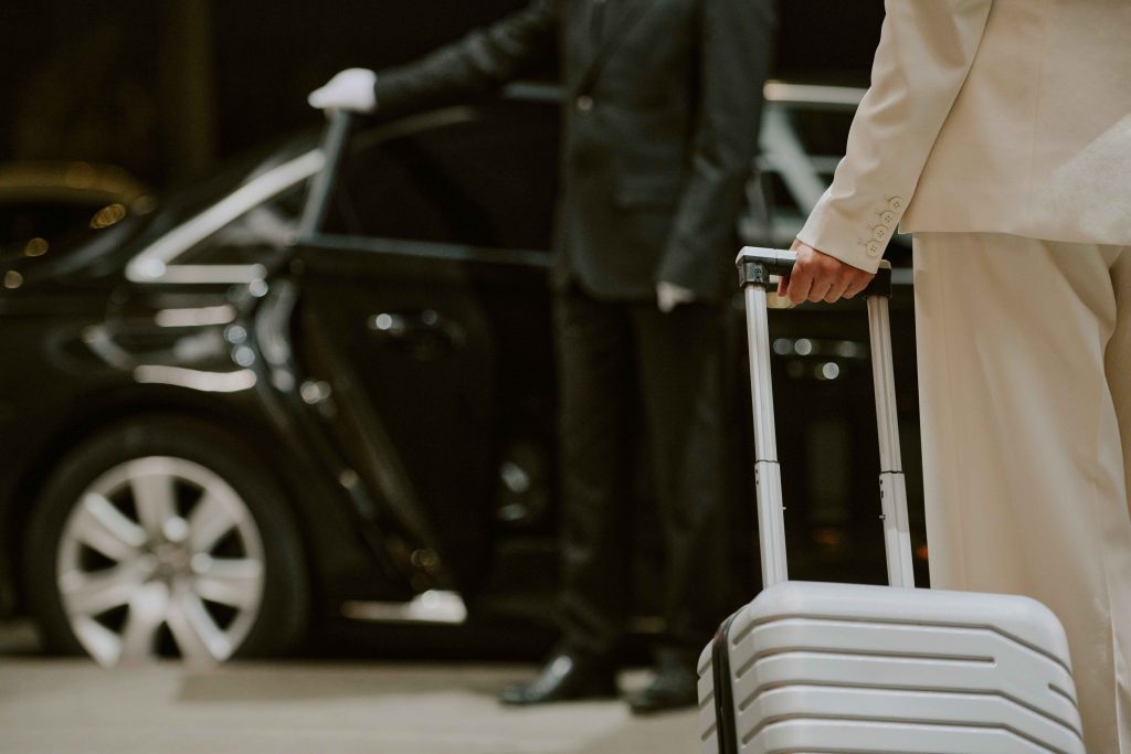 middle aged man arriving at luxury car with luggage