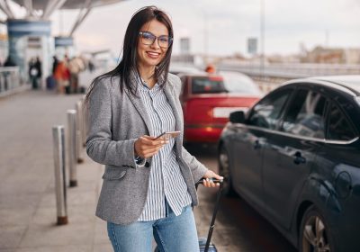 happy caucasian woman traveller in airport terminal is taking a taxi